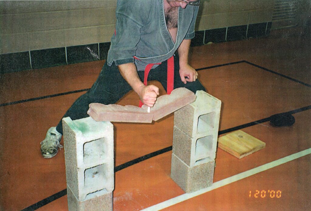 man breaking two boards with a tampon